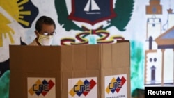A man stands at a voting booth at a polling station during parliamentary election in Caracas, Venezuela, Dec. 6, 2020. 