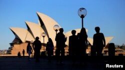 FILE - People walk in front of the Sydney Opera House, Australia, Nov. 2, 2016.