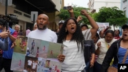 Luis Arroyo (kiri) membawa foto dua putranya yang hilang, Ismael dan Josué, saat turun ke jalan melakukan aksi protes bersama keluarganya di Guayaquil, Ekuador, pada 23 Desember 2024. (Foto: AP/Cesar Munoz)