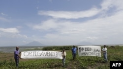 Activistas sostienen pancartas que dicen en español "El vendedor de la Patria Ortega" (I) y "Chinos salen" durante una protesta contra el proyecto de construcción de un canal interoceánico, en el municipio de San Jorge, a 4km de Rivas, Nicaragua, el 3 de octubre de 2014.