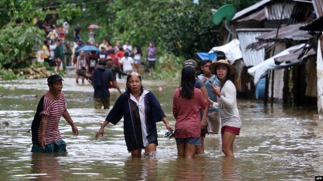 Villagers wade through a flooded street in Brgy Calingatngan, in Borongan, easterm Samar, central Philippines, Dec. 16, 2017.