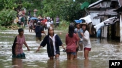 Villagers wade through a flooded street in Brgy Calingatngan, in Borongan, easterm Samar, central Philippines, Dec. 16, 2017.