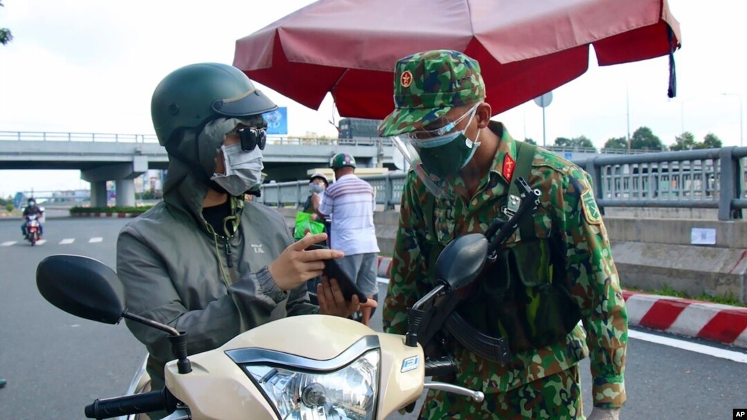 An army soldier checks identifications at a COVID-19 lockdown checkpoint in Ho Chi Minh City, Vietnam, Monday, Aug. 23, 2021. 