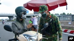 An army soldier checks identifications at a COVID-19 lockdown checkpoint in Ho Chi Minh City, Vietnam, Monday, Aug. 23, 2021. 