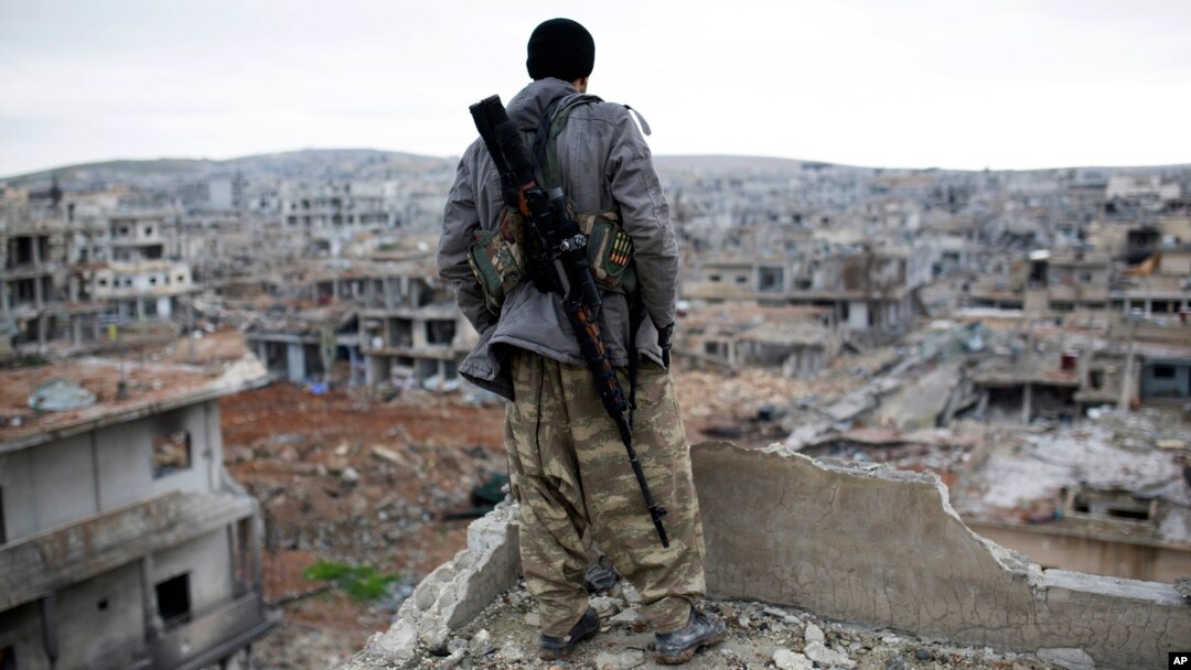 FILE - A Syrian Kurdish sniper looks at the rubble in the Syrian city of Kobani.