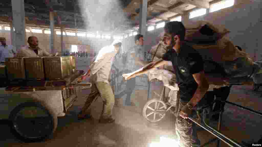 A Free Syrian Army fighter inspects purchases of civilians as they walk through a building to avoid snipers at Karaj al-Hajez crossing, Aleppo, Sept. 9, 2013.