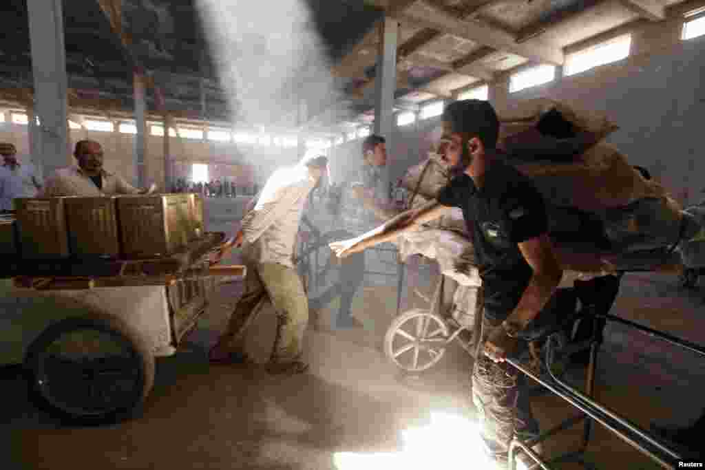 A Free Syrian Army fighter inspects purchases of civilians as they walk through a building to avoid snipers at Karaj al-Hajez crossing, Aleppo, Sept. 9, 2013.