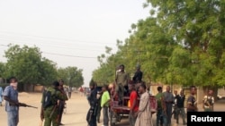 FILE - Local volunteers carrying weapons stand in the Jiddari Polo area in Maiduguri, Nigeria, after an attack by Boko Haram militants, April 27, 2018. A Boko Haram attack was blamed for 43 deaths near Maiduguri on Nov. 28, 2020.