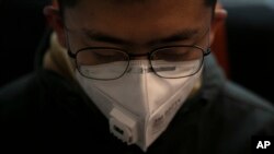 A man wears a mask as he travels on a train, Jan. 29, 2020, in the Odaiba district of Tokyo. Japanese officials say four evacuees on a flight from the Chinese city of Wuhan have a cough and fever. 