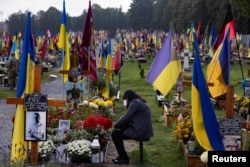 Seorang perempuan menangis saat dia duduk di kuburan di pemakaman militer Field of Mars saat Ukraina memperingati tentara yang tewas melawan invasi Rusia di Lviv, Ukraina, 1 Oktober 2023. (Foto: REUTERS/Thomas Peter)