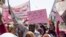 FILE - Protesters carry posters in Arabic that say, "Freedom, justice, and peace, and the revolution is the choice of the people," at the sit-in outside the military headquarters, in Khartoum, Sudan, May 2, 2019.