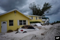 A car   sits half-buried successful  soil  arsenic  Bradenton Beach, Fla., which was successful  the process   of cleaning up   aft  Hurricane Helene, arsenic  Hurricane Milton approaches connected  Anna Maria Island, Oct. 8, 2024.