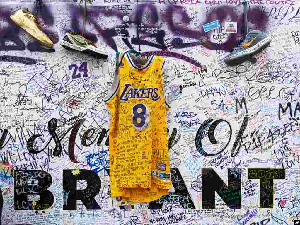 Sneakers and a Los Angeles Lakers jersey with the number 8 worn by NBA star Kobe Bryant hang at a memorial for Bryant in Los Angeles, Feb. 2, 2020, a week after he was killed in a helicopter crash. 