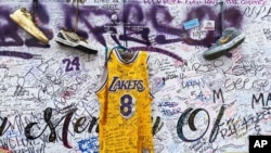 Sneakers and a Los Angeles Lakers jersey with the number 8 worn by NBA star Kobe Bryant hang at a memorial for Bryant in Los Angeles, Feb. 2, 2020, a week after he was killed in a helicopter crash. 