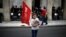 A refugee child holds a flag during a protest, called by the 'United against Rascism and the Fascist Threat' movement, demanding better conditions for refugees in the Greek camps, in front of the City Hal in Athens, June 9, 2016.