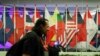 A journalist walks past ASEAN member country flags at the Suntec Convention Centre during the 33rd ASEAN summit in Singapore, Monday, Nov. 12, 2018. (AP Photo/Yong Teck Lim)