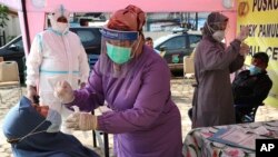 Para nakes mengambil sampel dari hidung para pemudik sebelum kembali memasuki ibu kota Jakarta, di sebuah pos pemeriksaan di Tangerang, 19 Mei 2021. (AP Photo/Tatan Syuflana)