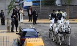 FILE - Local residents pay their respects as a hearse carrying the coffin of Mark Duggan goes ahead of the funeral cortege traveling through the Broadwater Farm estate in Tottenham, north London, Sept. 9, 2011.