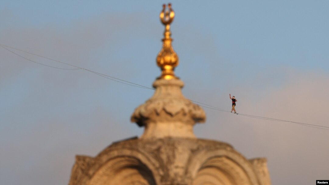 Atlet Estonia Jaan Roose terlihat di belakang Masjid Ortakoy Mecidiye saat ia berjalan di atas slackline melintasi Jembatan Martir 15 Juli (Jembatan Bosphorus), menyeberang dari sisi Asia kota ke sisi Eropa, di Istanbul, Turki, 15 September 2024. (Murad Sezer/REUTERS)