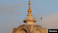 Atlet Estonia Jaan Roose terlihat di belakang Masjid Ortakoy Mecidiye saat ia berjalan di atas slackline melintasi Jembatan Martir 15 Juli (Jembatan Bosphorus), menyeberang dari sisi Asia kota ke sisi Eropa, di Istanbul, Turki, 15 September 2024. (Murad Sezer/REUTERS)