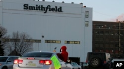 FILE - Employees and family members protest outside the Smithfield Foods processing plant in Sioux Falls, South Dakota, April 9, 2020, demanding stronger protective measures against the coronavirus. 