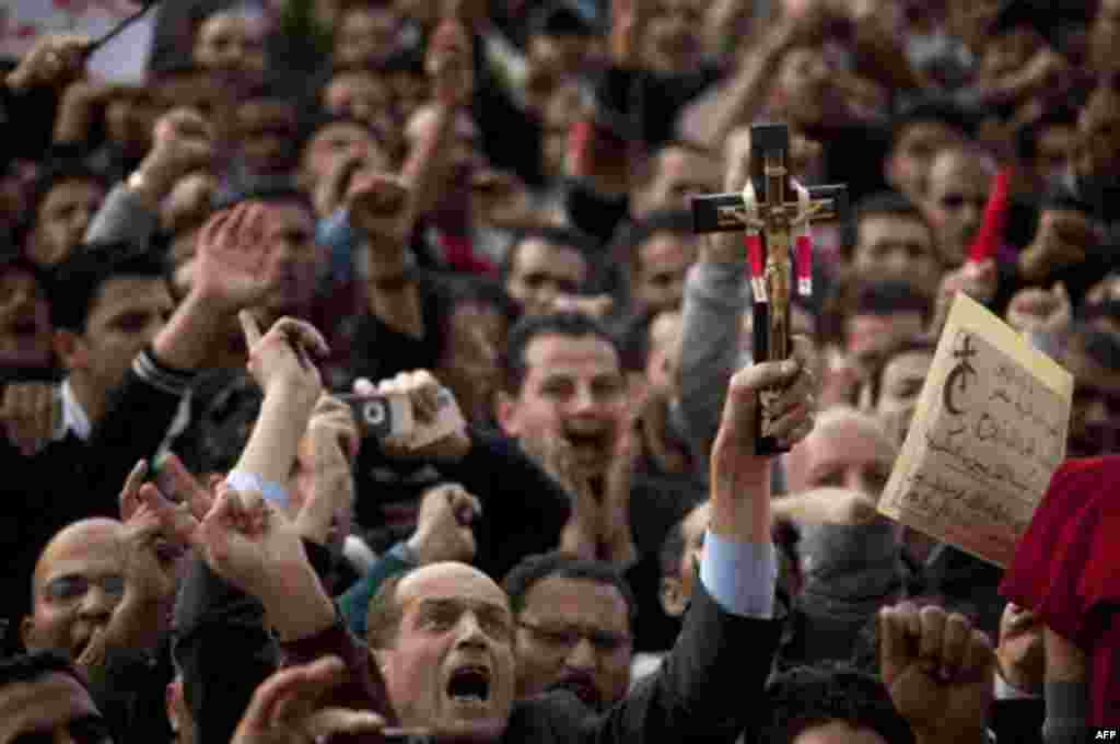 An anti-government protestor holds a Christian cross as others shout slogans during a demonstration at Tahrir Square in Cairo, Egypt, Wednesday, Feb. 9, 2011. Protesters appear to have settled in for a long standoff, turning Tahrir Square into a makeshift