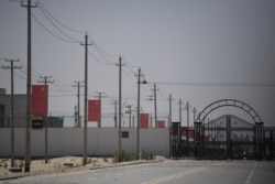 FILE - Chinese flags line on a road leading to a facility believed to be a re-education camp where mostly Muslim ethnic minorities are detained, on the outskirts of Hotan in China's northwestern Xinjiang region, May 31, 2019.