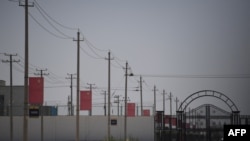 FILE - Chinese flags line on a road leading to a facility believed to be a re-education camp where mostly Muslim ethnic minorities are detained, on the outskirts of Hotan in China's northwestern Xinjiang region, May 31, 2019.