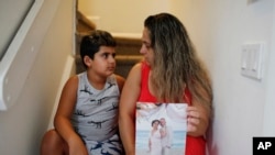 Barbara Rodriguez and her son, Nolan Aragon, 9, pose for a photograph in Hialeah, Fla., Aug. 6, 2019. Rodriguez is holding a wedding photograph of her and her husband, Pablo Sanchez, who is in detention in the U.S. and facing deportation to Cuba.