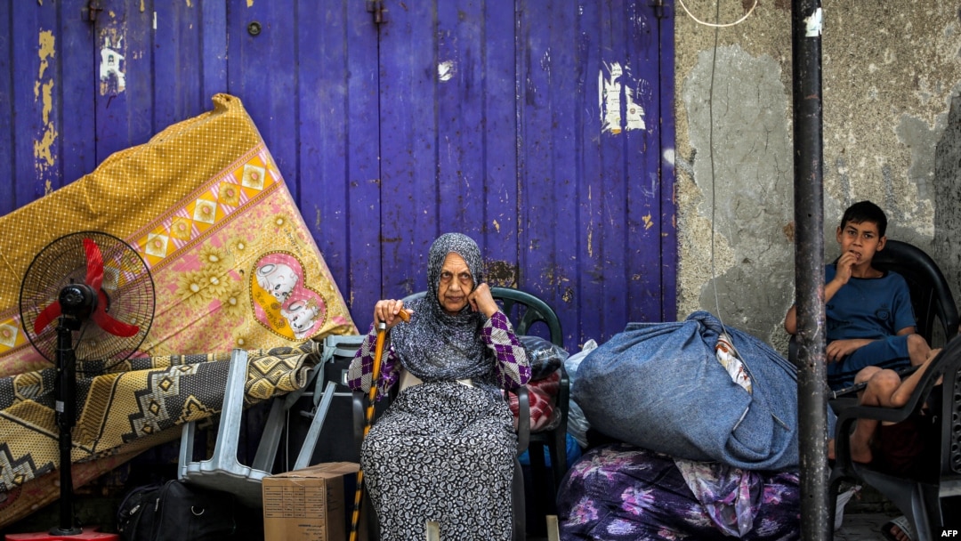 Seorang perempuan dan anak menunggu dengan barang-barangnya sebelum dievakuasi dari Rafah di Jalur Gaza selatan pada 11 Mei 2024, di tengah konflik di wilayah Palestina antara Israel dan Hamas. (Foto: AFP)