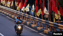 Seorang pria mengendarai sepeda motor melewati jembatan layang yang dihiasi bendera-bendera partai politik menjelang pemilu, Jakarta, 6 April 2019. (Foto: Reuters)