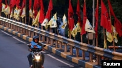 Seorang pria mengendarai sepeda motor melewati jembatan layang yang dihiasi bendera-bendera partai politik menjelang pemilu, Jakarta, 6 April 2019. (Foto: Reuters)