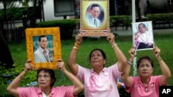 Thais hold portraits of Thai King Bhumibol Adulyadej at Siriraj Hospital where the king is being treated in Bangkok, Thailand, Oct. 11, 2016. 