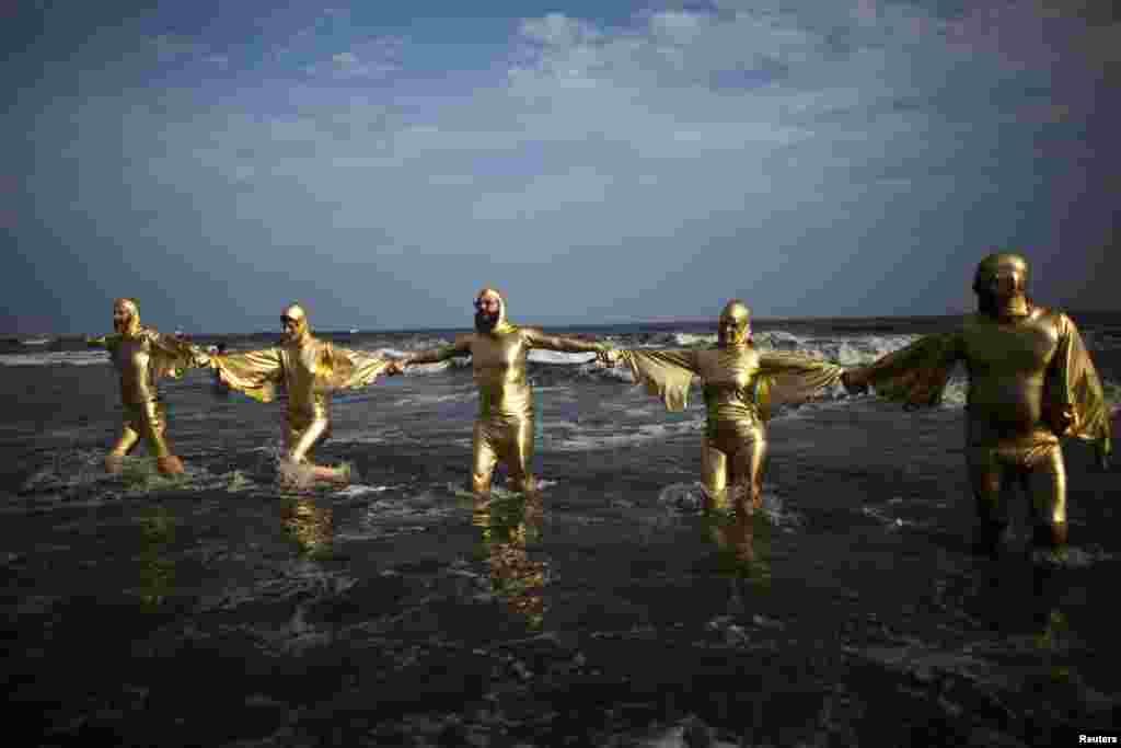 Members of Ghost of a Dream go into the sea after taking part in the second annual Artist Sandcastle Competition in Rockaway, New York, Aug. 9, 2013.