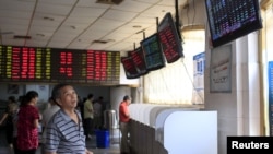 FILE - Investor looks at electronic boards showing stock information at a brokerage house in Shanghai, China, Sept. 1, 2015.