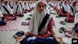 Siswi Muslim di India berlatih yoga di sekolah untuk perayaan Hari Yoga Internasional pertama di Ahmadabad, India (17/6). (AP/Ajit Solanki)