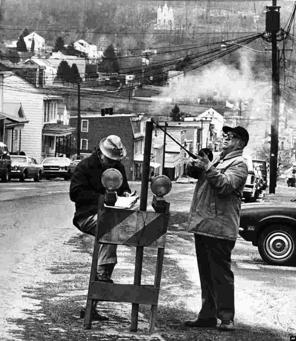 FILE - An April, 1981 photo shows U.S. Bureau of Mines&#39; John Stockalis (R) and Dan Lewis dropping a thermometer through a hole on Main Street in Centralia, Pa., to measure heat from a shaft mine blaze that had been burning under the town since 1962. (AP)