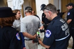 On the 2019 Catholic Day of Action, Catholic University of America Professor Julia Young looks on as her father, Attorney Malcolm Young, gets arrested for civil disobedience inside a U.S. Senate office building near the U.S. Capitol in Washington. (Courtesy - Patrick G. Ryan, CUA Photographer)