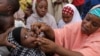 FILE- In this April 13, 2014 file photo, an unidentified health official administers a polio vaccine to a child in Kawo Kano, Nigeria. 