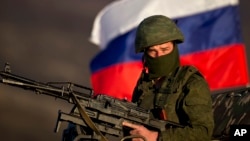 FILE - A pro-Russian soldier is back-dropped by Russia flag while manning a machine-gun outside an Ukrainian military base in Perevalne, Ukraine, March 15, 2014. 