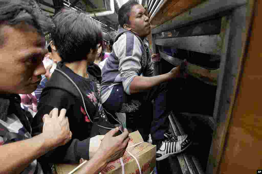Indonesian men struggle to board a packed train through a window at Senen station in Jakarta, Indonesia, September 2010 (AP)
