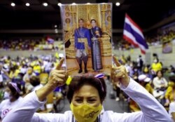 A member of Thai right-wing group "Thai Pakdee" (Loyal Thai) holds a picture of King Maha Vajiralongkorn with Queen Suthida attend a rally in support of the government and the monarchy, in Bangkok, Thailand, Aug. 30, 2020.