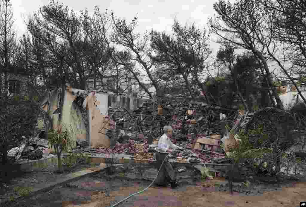 Firefighters inspect a burned area in Mati, east of Athens, Tuesday, July 24, 2018.