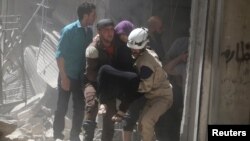 Civil defense members evacuate a woman from a damaged building after airstrikes in the rebel held area of old Aleppo, Syria, April 22, 2016.