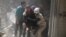 Civil defense members evacuate a woman from a damaged building after airstrikes in the rebel held area of old Aleppo, Syria, April 22, 2016.
