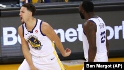 Klay Thompson, à gauche, avec son coéquipier Draymond Green, célébrant une victoire des Golden State Warriors, Oakland, Californie, le 26 mai 2018. 