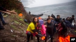 A volunteer holds a baby who cries after the arrival of refugees and migrants from the Turkish coast to the Skala Sykaminias village on the northeastern Greek island of Lesbos, Oct. 23, 2015.