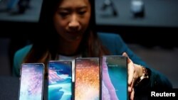 FILE - A Samsung employee arranges the new Samsung Galaxy S10e, S10, S10+ and the Samsung Galaxy S10 5G smartphones at a press event in London, Britain Feb. 20, 2019.