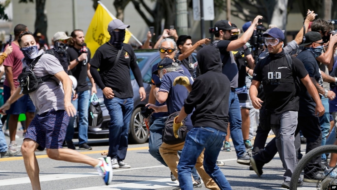 Demonstran anti vaksin (kiri) terlibat pertikaian dengan orang-orang yang berlawanan pendapat dengan mereka dalam sebuah unjuk rasa anti vaksin di depan Balai Kota Los Angeles, AS, pada 14 Agustus 2021. (Foto: AP/Damian Dovarganes)