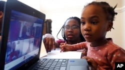 FILE - Lear Preston, 4, who attends Scott Joplin Elementary School, participates in her virtual classes as her mother, Brittany Preston, background, assists at their residence in Chicago's South Side, Feb. 10, 2021.